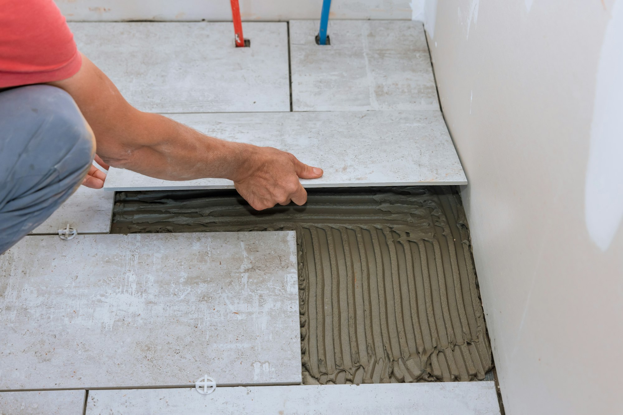 Home construction working with placing ceramic floor tiles on adhesive