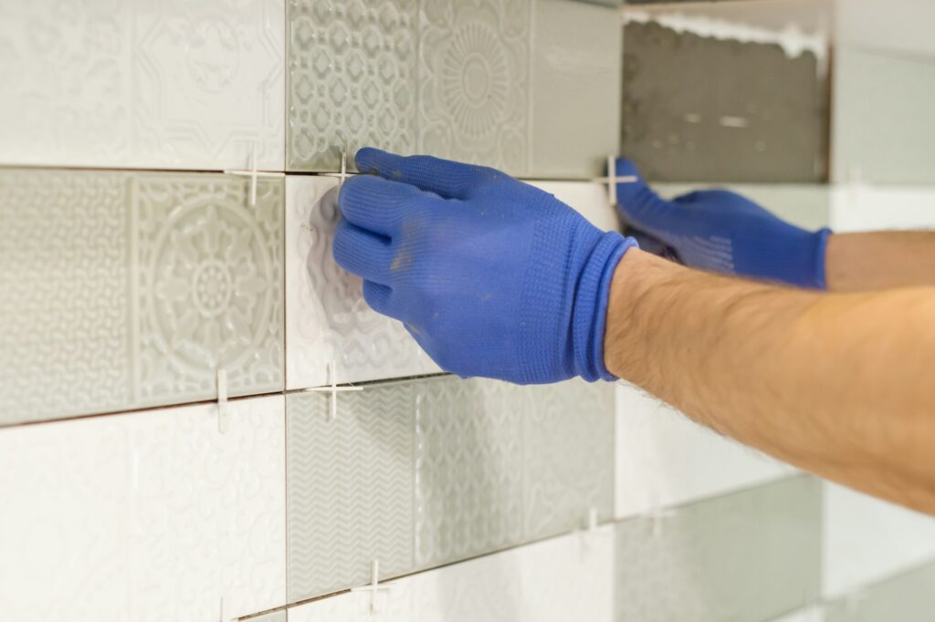 Installing ceramic tiles on the wall in kitchen.