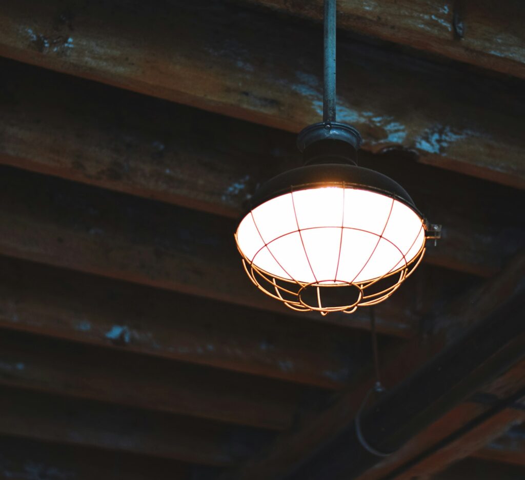 Rustic industrial style lighting hanging from a ceiling with old wooden beams