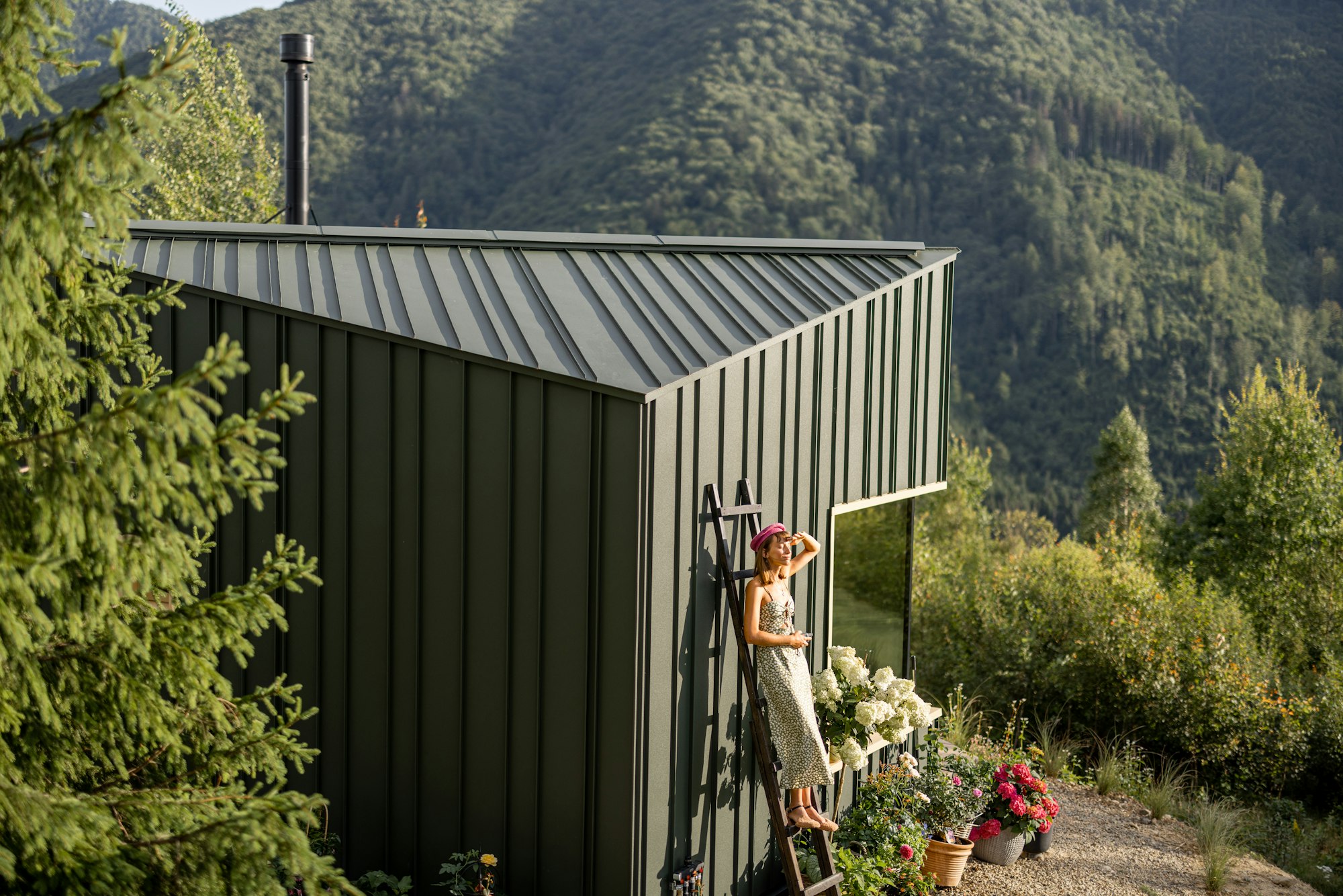 Woman on Ladder by Eco-Friendly House in Green Mountain Garden