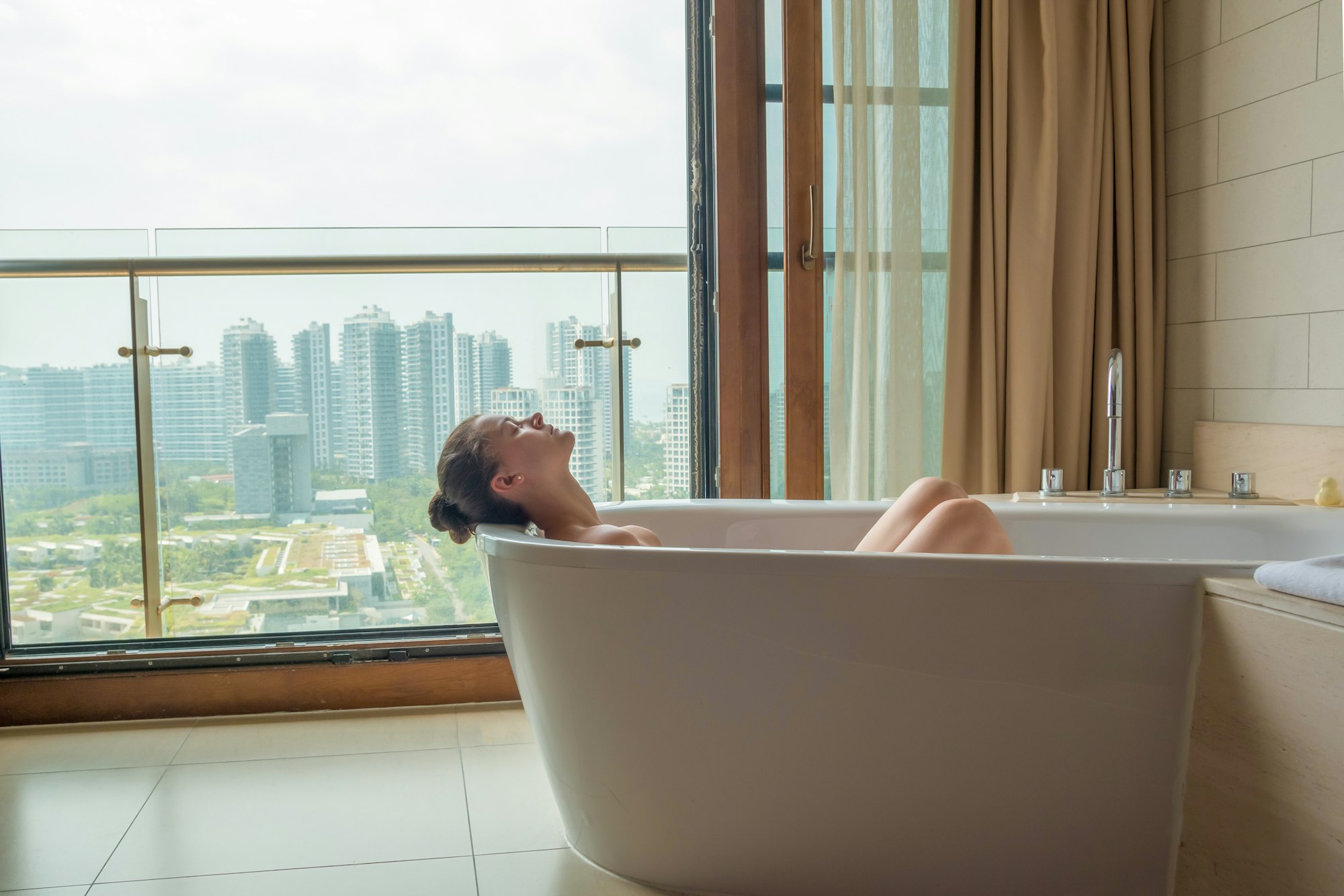 Young woman in luxury bathroom with city view