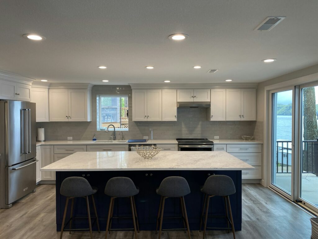 A modern kitchen with a grey and navy blue island at the lake