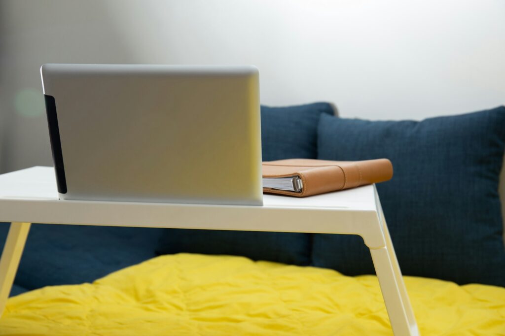 Tablet, and brown notebook on a white foldable desk at home - work from home concept