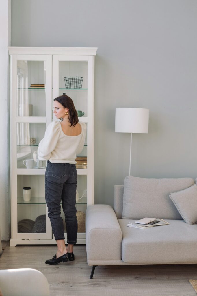 View from behind of stylish woman standing near tall glass display cabinet.