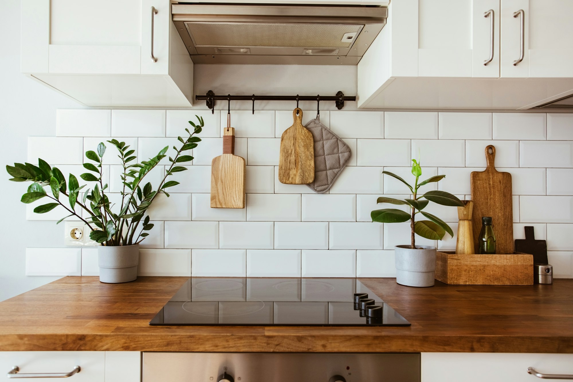 Hanging kitchen with white tiles wall and wood tabletop.Green plant on kitchen background