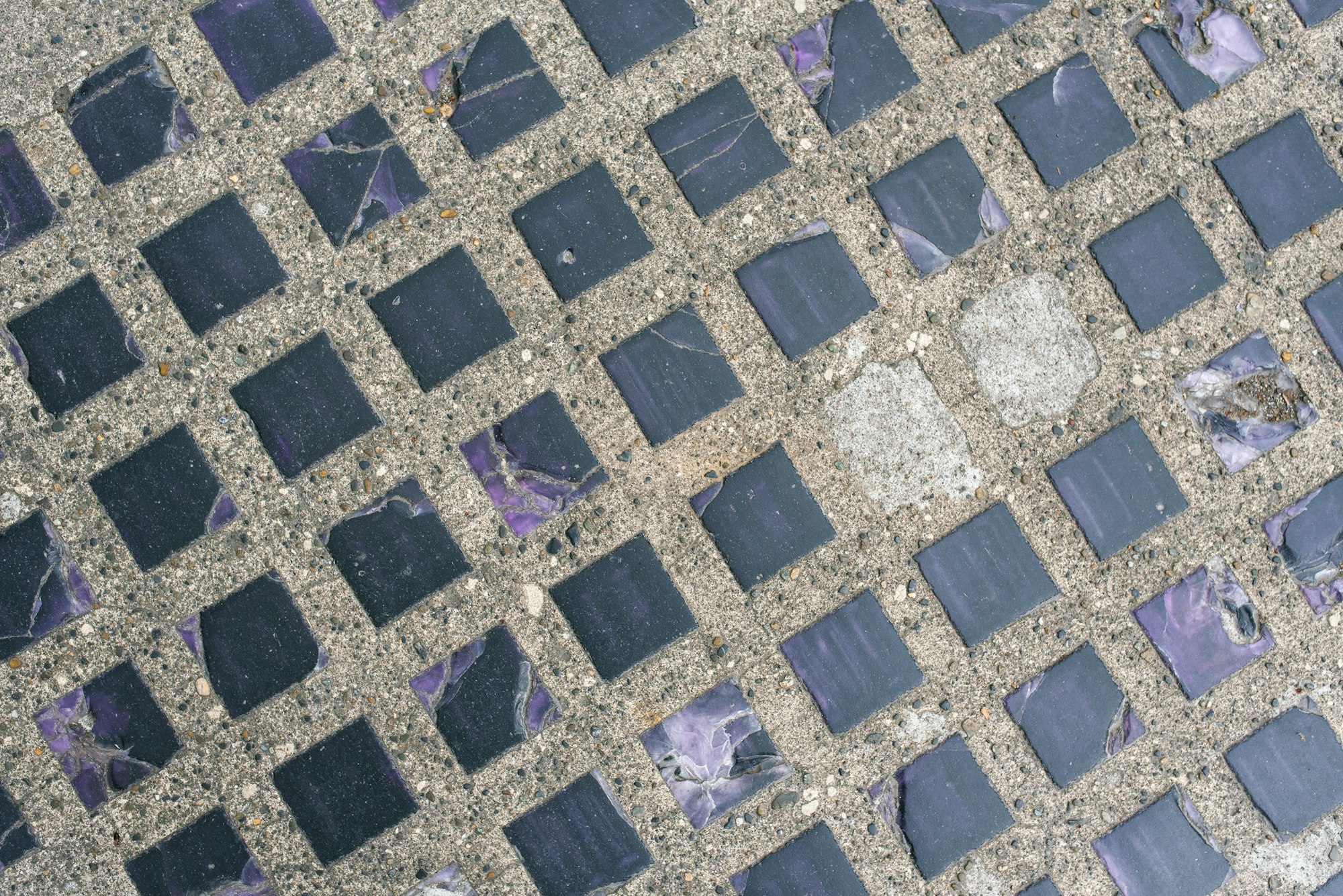 Purple Glass Tiles Embedded in Asphalt. Original Background for copy space.