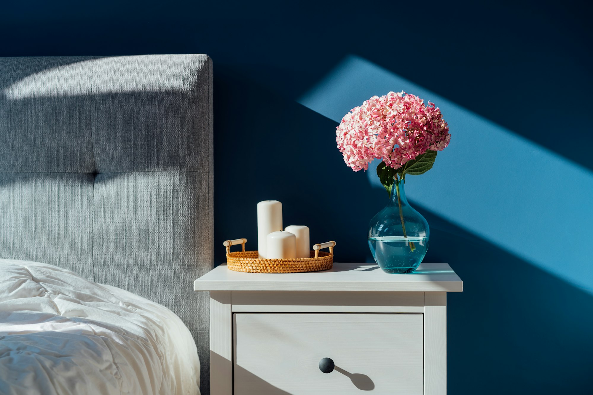 Stylish modern bedroom in dark colors. Cozy interior with navy blue walls, home decor.